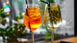 Ein Glas Aperol Spritz neben einem Glas Hugo