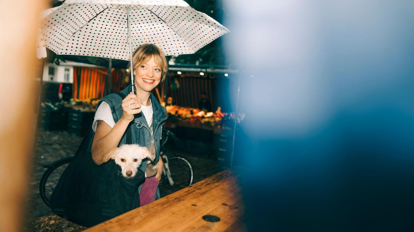 Heike Makatsch mit Regenschirm und ihrem Hund in der Handtasche