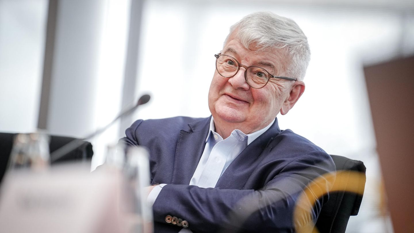 Joschka Fischer, ein Mann mit Brille und grauem Haar, sitzt mit verschränkten Armen auf einem Stuhl