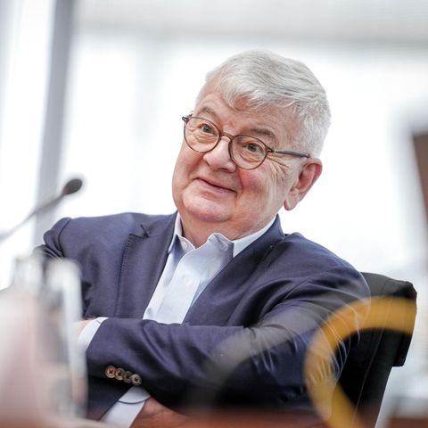 Joschka Fischer, ein Mann mit Brille und grauem Haar, sitzt mit verschränkten Armen auf einem Stuhl