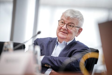 Joschka Fischer, ein Mann mit Brille und grauem Haar, sitzt mit verschränkten Armen auf einem Stuhl