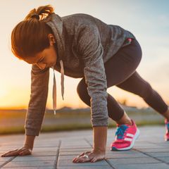Eine Frau wärmt sich fürs Joggen auf.