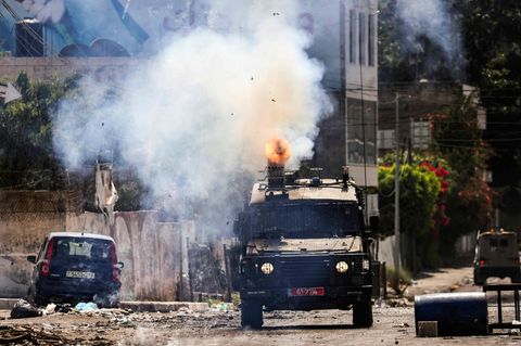 Ein israelisches Panzerfahrzeug feuert in der Stadt Dschenin im besetzten Westjordanland Tränengas ab