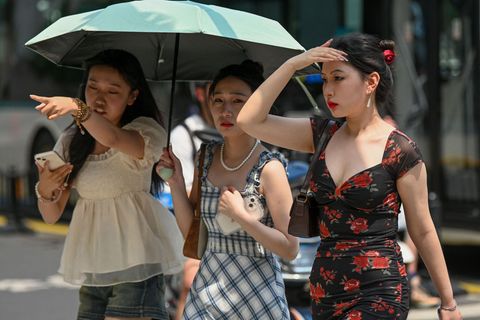 Frauen nutzen einen Regenschirm, um sich bei heißem Wetter in Shanghai vor der Sonne zu schützen.