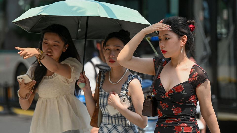 Frauen nutzen einen Regenschirm, um sich bei heißem Wetter in Shanghai vor der Sonne zu schützen.