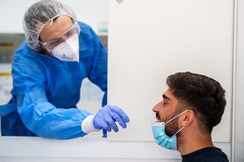 Ein Mitarbeiter einer Teststation führt einen Corona-Test durch