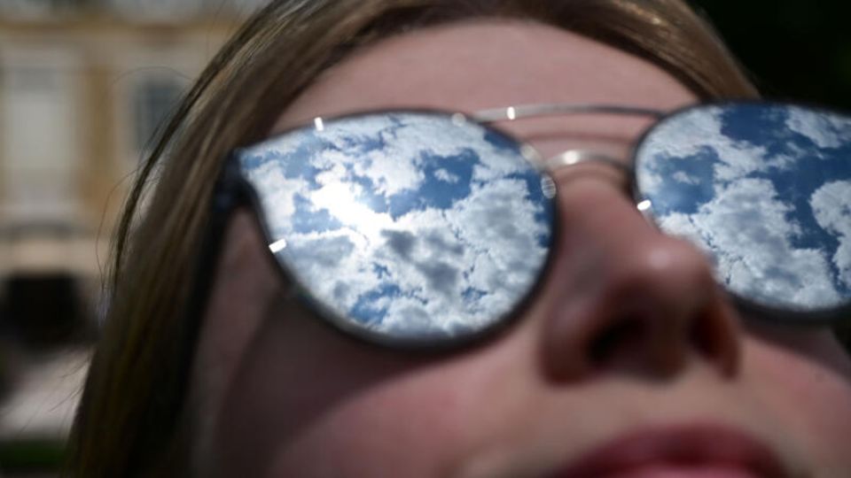 Geo-Engineering: Eine Frau schaut mit Sonnenbrille in den Himmel