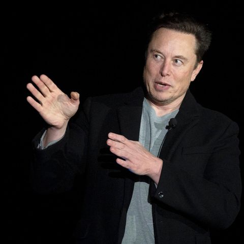 Elon Musk zeigt mit beiden Händen nach rechts und schaut mit großen Augen in die Richtung