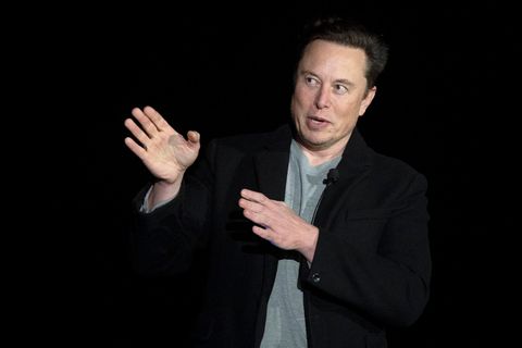 Elon Musk zeigt mit beiden Händen nach rechts und schaut mit großen Augen in die Richtung