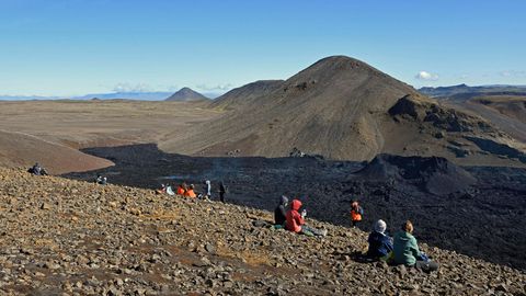 Touristen schauen am Fagradalsfjall auf Island auf ein rauchendes Lavafeld (Archivfoto)
