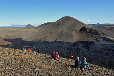 Touristen schauen am Fagradalsfjall auf Island auf ein rauchendes Lavafeld (Archivfoto)