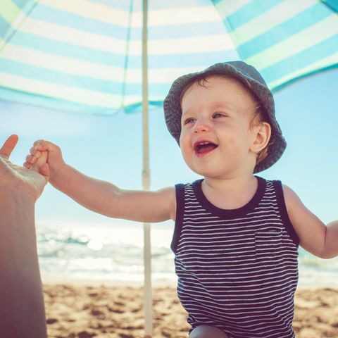 Ein kleiner Junge am Strand unter einem Sonnenschirm