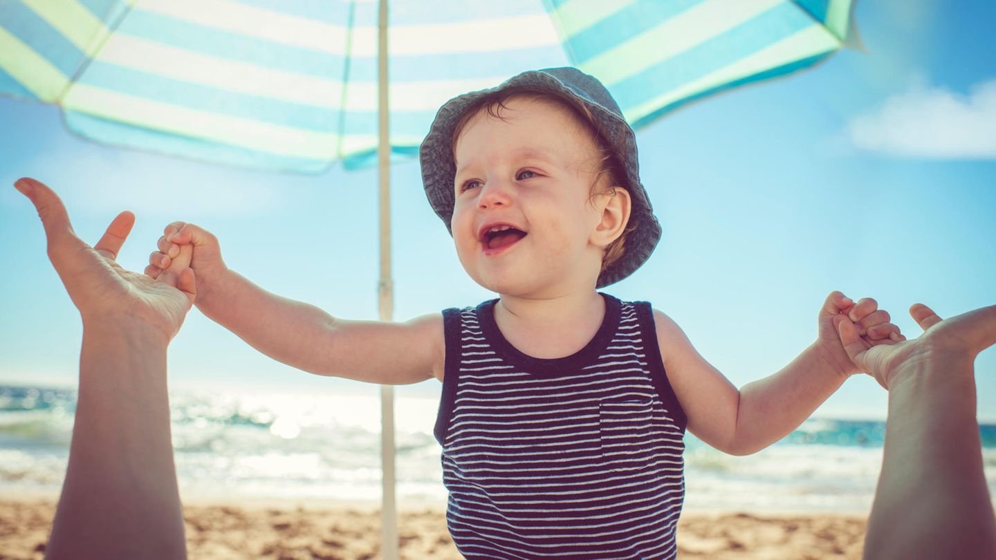 Ein kleiner Junge am Strand unter einem Sonnenschirm