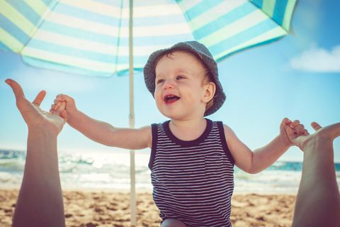 Ein kleiner Junge am Strand unter einem Sonnenschirm
