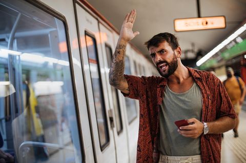 Ein Mann ärgert sich vor einem Nahverkehrszug
