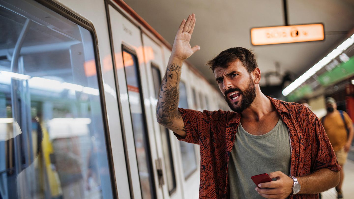Ein Mann ärgert sich vor einem Nahverkehrszug