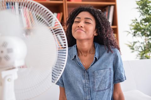 Frau kühlt sich mit Ventilator ab