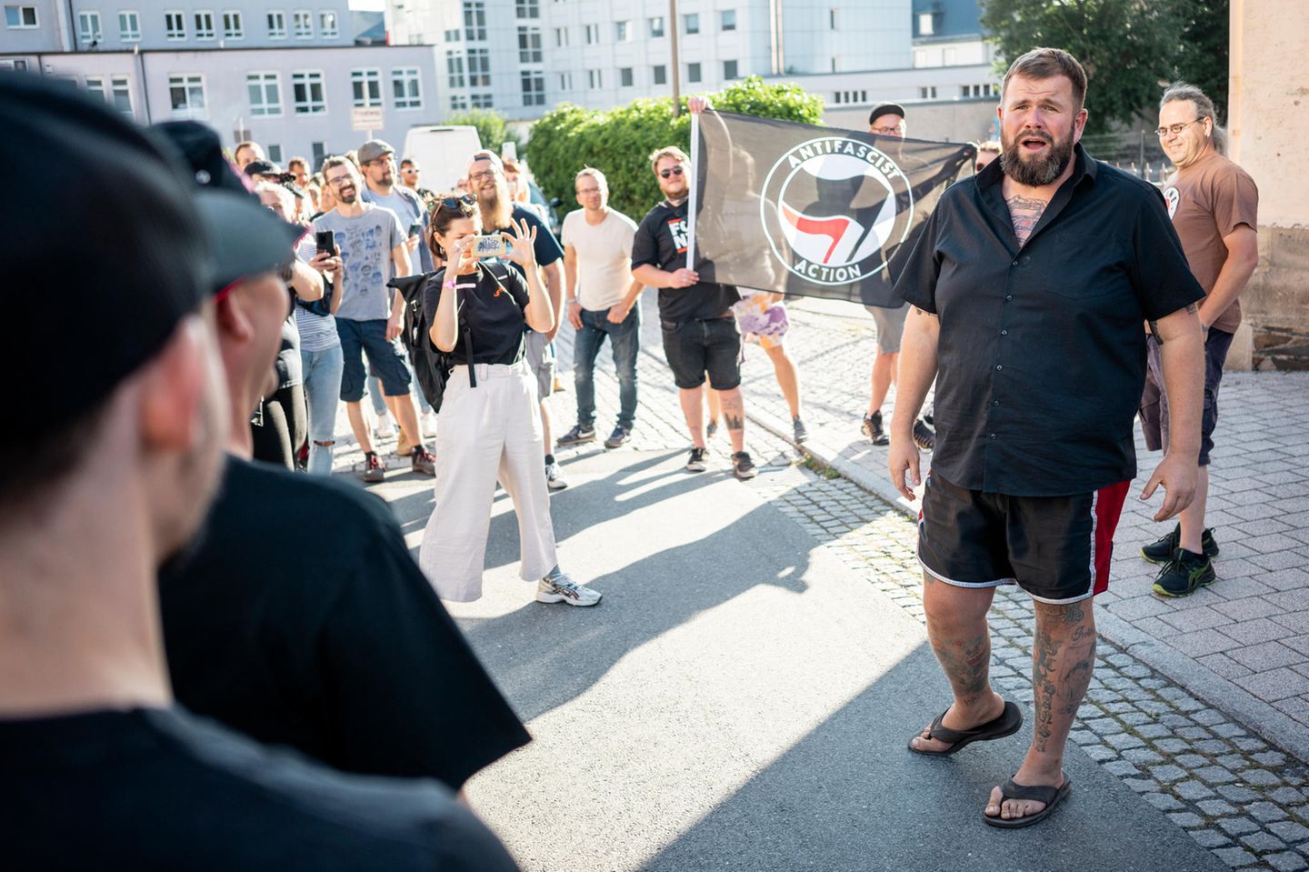 Ein Mann in kurzer Hose steht vor einer Menge und redet. Es ist "Monchi", der Sänger von Feine Sahne Fischfilet