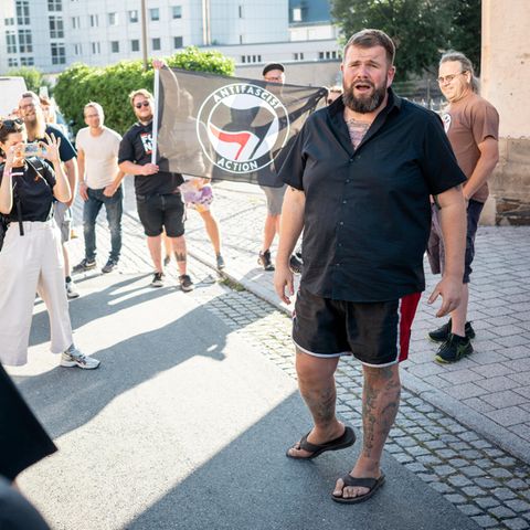 Ein Mann in kurzer Hose steht vor einer Menge und redet. Es ist "Monchi", der Sänger von Feine Sahne Fischfilet