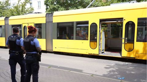 Polizisten stehen vor der Straßenbahn in Dresden, in der ein Mann niedergestochen wurde