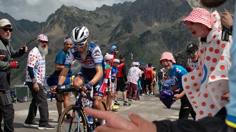 Tour de France. Ein Radfahrer fährt einen Berg hinauf. Menschen am Straßenrand feuern ihn an.