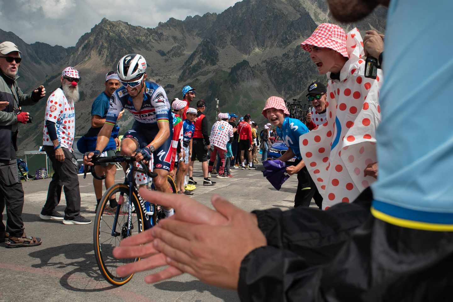 Tour de France. Ein Radfahrer fährt einen Berg hinauf. Menschen am Straßenrand feuern ihn an. Tour de France. Ein Radfahrer fährt einen Berg hinauf. Menschen am Straßenrand feuern ihn an.