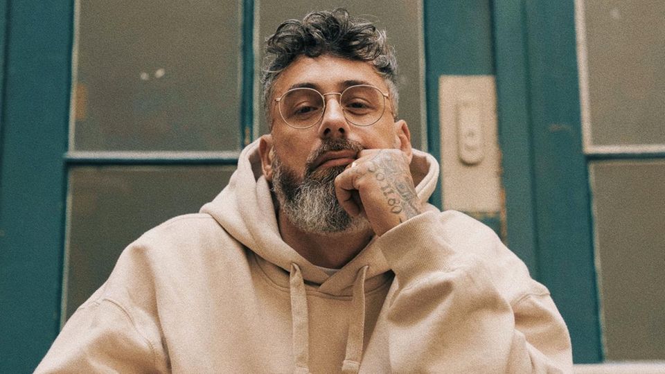 Sido in beigem Hoodie auf einer Treppe sitzend