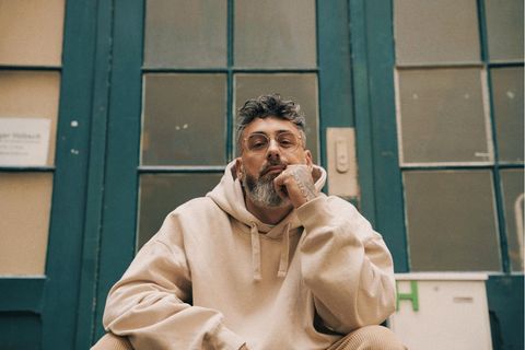 Sido in beigem Hoodie auf einer Treppe sitzend