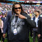 Jay-Z seht mit Sonnebrille und Pullover in einem vollen Stadion