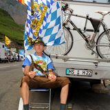 Ein Mann mit Lederhose, Wurst und Stulle am Rande der Tour de France