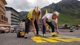 Fans der Tour de France malen mit dicken gelben Farbrollen motivierende Sprüche auf die Strecke