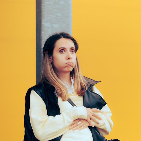 Eine Frau plagt sich mit Übelkeit, sie hält sich den Bauch