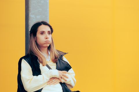 Eine Frau plagt sich mit Übelkeit, sie hält sich den Bauch