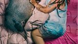 Eine Mutter im Kleid liegt in ihrem Bett, neben sich ihr Hausschwein