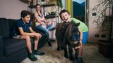 Drei Geschwister freuen sich in ihrem Wohnzimmer über ihr Pony