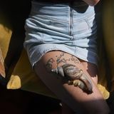 Auf dem Oberschenkel einer Frau im kurzen Jenasrock sitzt ihre Riesenschnecke