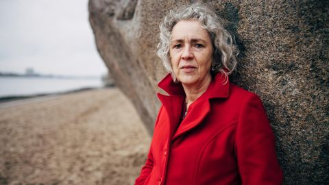 Portrait einer rund 60-jährigen Frau mit grauen Locken und rotem Mantel