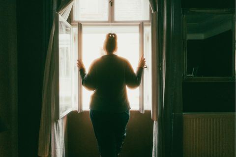 Thema Häusliche Gewalt: Einsame Frau steht am Fenster