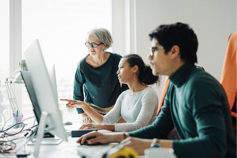 Verschiedene Generationen sitzen vor einem Computer in einem Unternehmen
