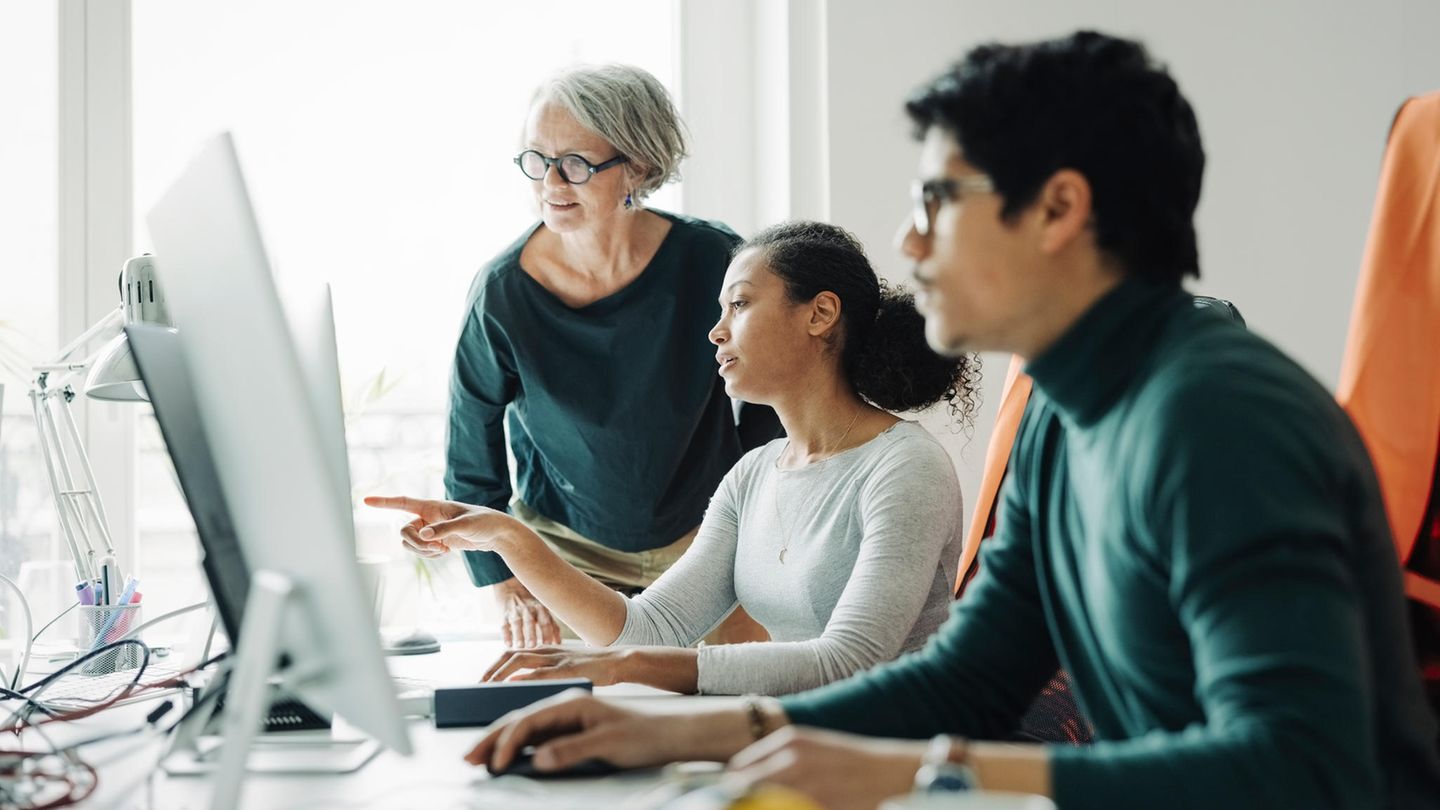 Verschiedene Generationen sitzen vor einem Computer in einem Unternehmen