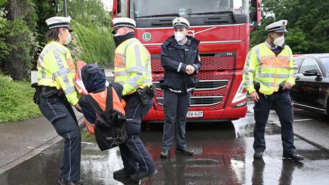 Polizisten tragen einen Klimaaktivisten von einer Straße, wo er einen roten LKW blockiert hatte