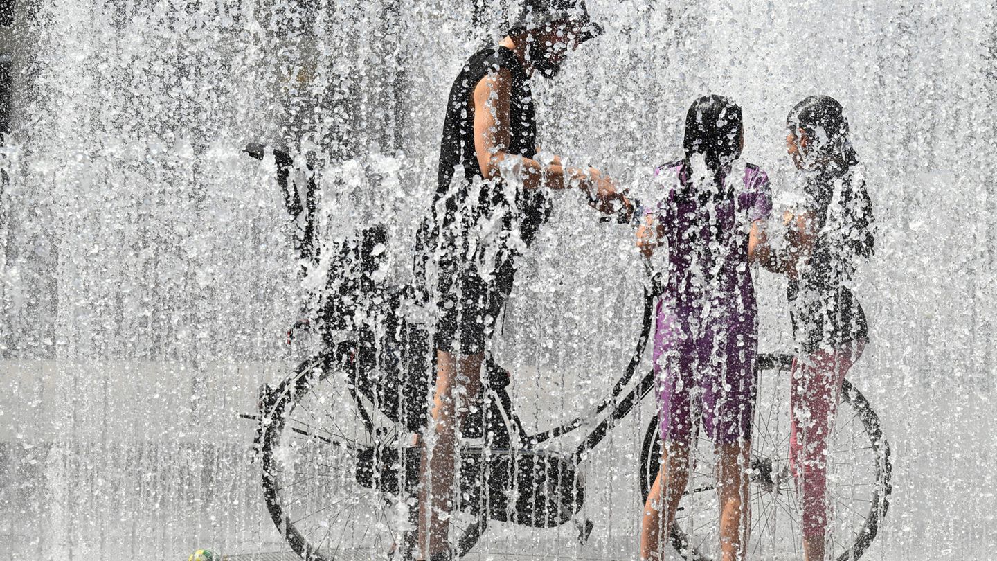 Ein Radfahrer fährt bei den heißen Temperaturen durch einen Springbrunnen um sich abzukühlen. Im unterfränkischen Kitzingen wurde mit 38,0 Grad die bisher höchste Temperatur in diesem Jahr gemessen.