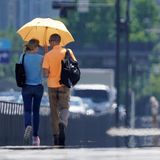Menschen gehen bei großer Hitze auf dem Bürgersteig entlang des Kaiserpalastgartens in der japanischen Hauptstadt. Dort stieg das Quecksilber zum ersten Mal seit Jahresbeginn auf über 35 Grad.
