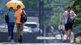 Menschen gehen bei großer Hitze auf dem Bürgersteig entlang des Kaiserpalastgartens in der japanischen Hauptstadt. Dort stieg das Quecksilber zum ersten Mal seit Jahresbeginn auf über 35 Grad.