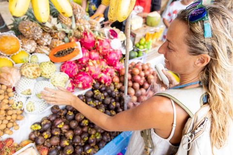 Frau wählt bei eienr Fernreise an einem Straßenstrand Obst aus