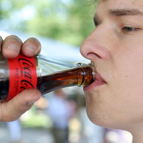 Junger Mann trinkt Cola zero