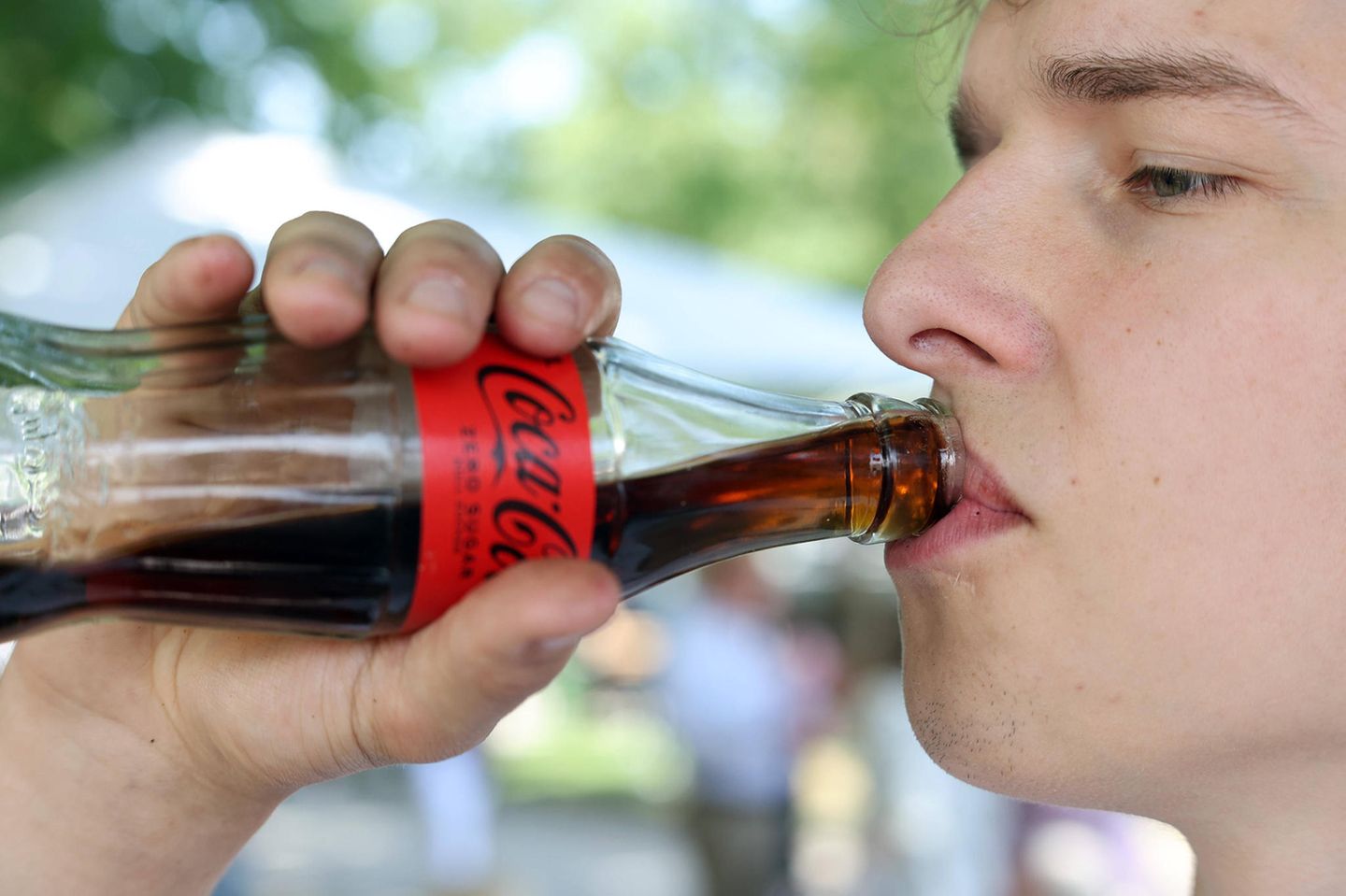 Junger Mann trinkt Cola zero