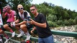 Pogacars Edelhelfer Matteo Trentin (M.) lässt sich von einem Fan fotografieren, während er auf die Weiterfahrt wartet.