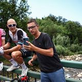 Pogacars Edelhelfer Matteo Trentin (M.) lässt sich von einem Fan fotografieren, während er auf die Weiterfahrt wartet.