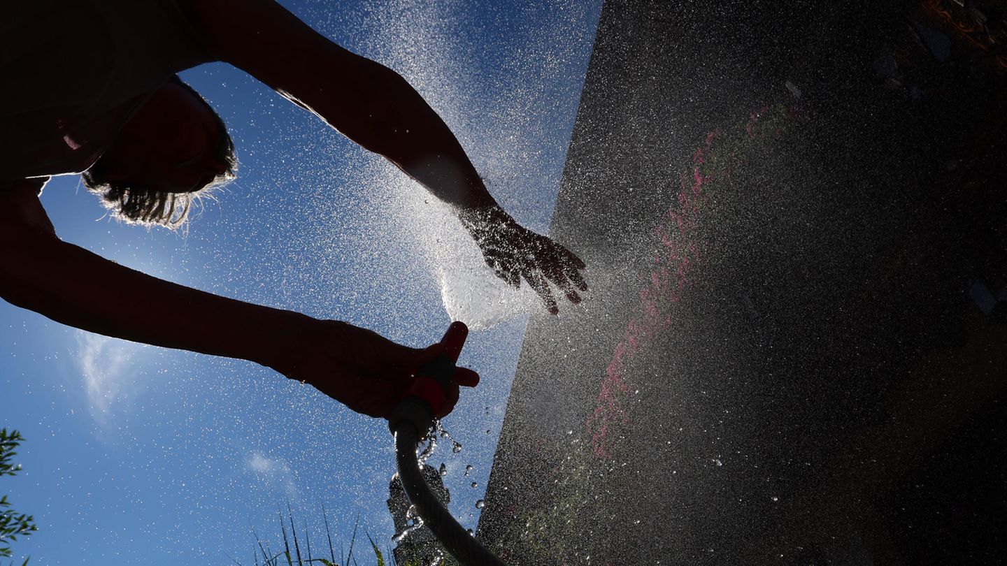 Im bayerischen Kaufbeuren kühlt sich eine Frau in einem Garten mit Wasser aus einem Gartenschlauch ab